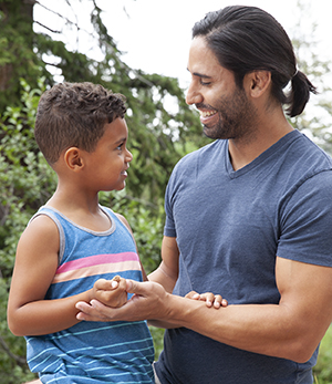 Man and boy smiling outside.