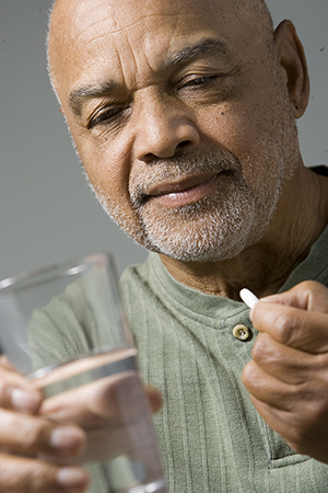 Man holding pill and glass of water.