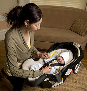 Woman securing baby in carrier.