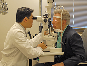 Healthcare provider examining man's eyes with slit lamp.