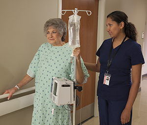 Healthcare provider walking with woman in hospital hallway.