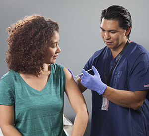 Healthcare provider giving injection in woman's arm.
