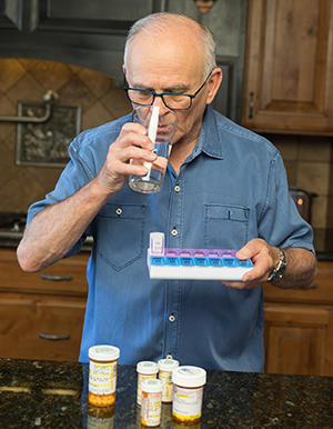 Man taking pills in kitchen.