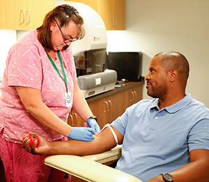 Health care provider drawing blood from man's arm.