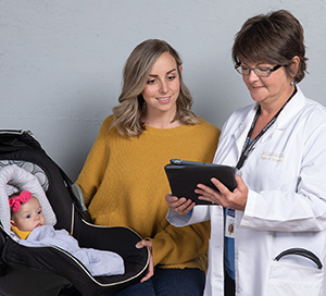 Woman with baby in carrier talking to healthcare provider.