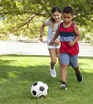 Girl and boy playing with soccer ball.