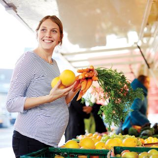 Pregnant woman buying fresh produce at the market