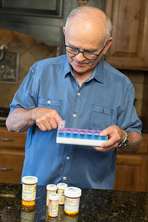 Man taking pills in kitchen.